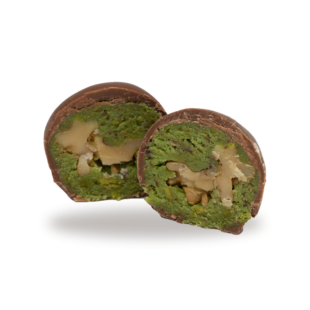 A milk chocolate Pistachio with Walnut broken open, showing the filling inside
