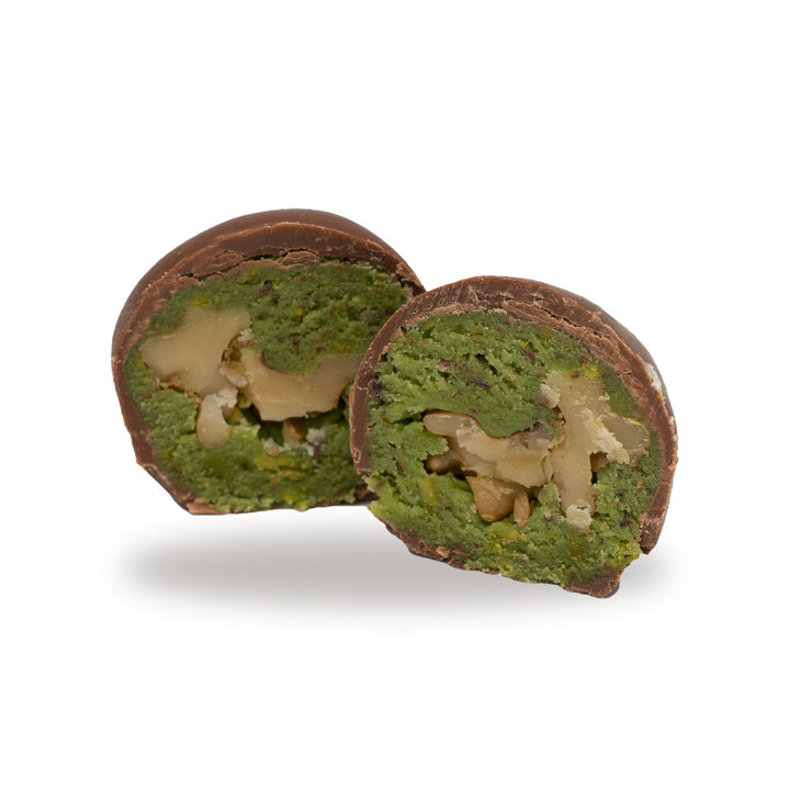 A milk chocolate Pistachio with Walnut broken open, showing the filling inside