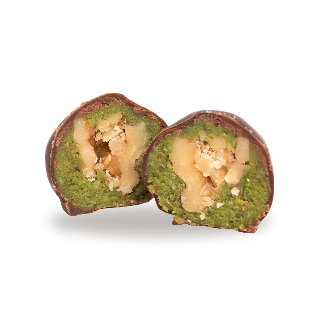 A dark chocolate Pistachio with Walnut broken open, showing the filling inside