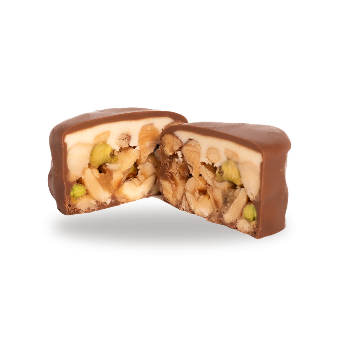 A milk chocolate Snayniyeh broken open, showing the cashew and pistachio inside