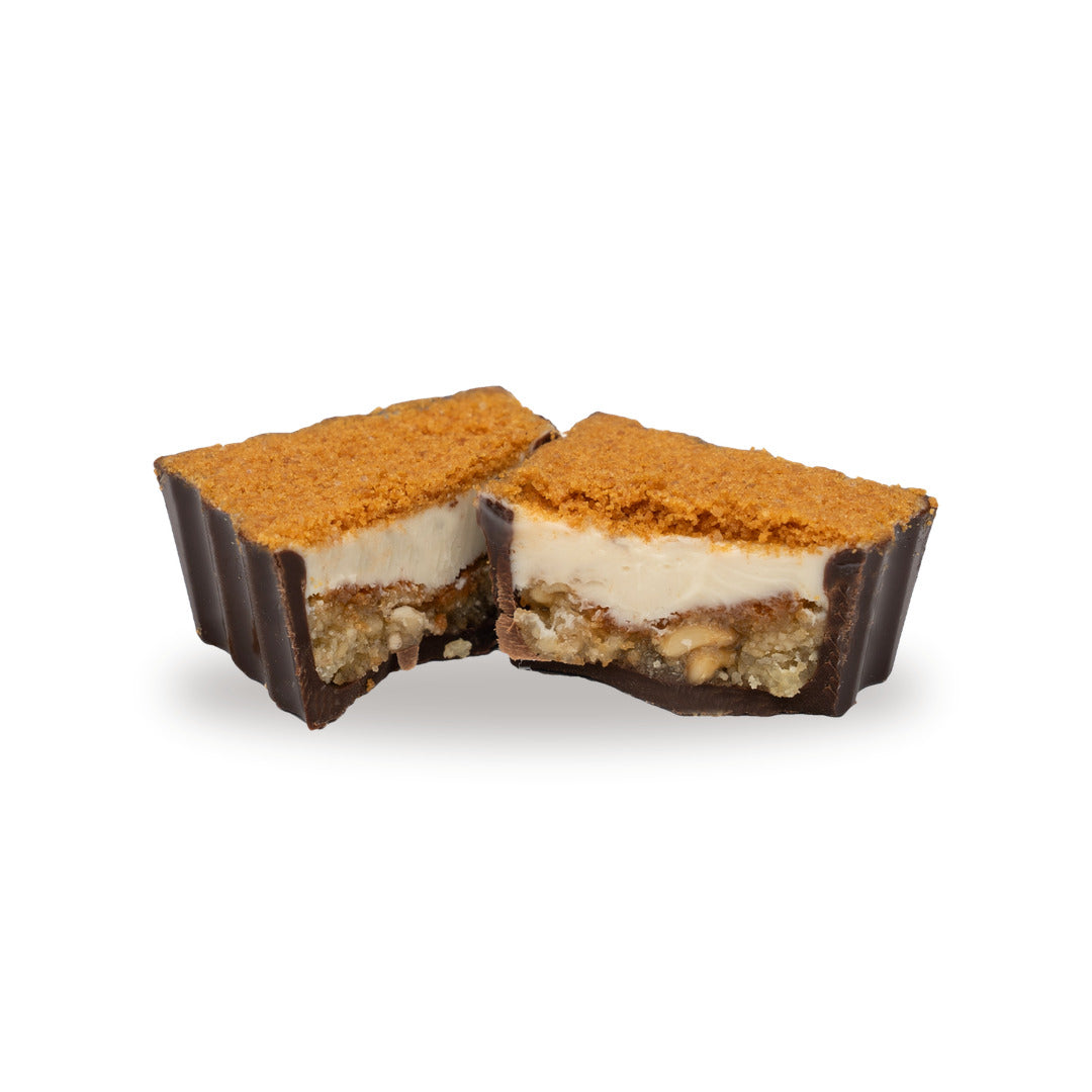 A dark chocolate Kenefe Caramel Biscuit broken open, showing the filling inside