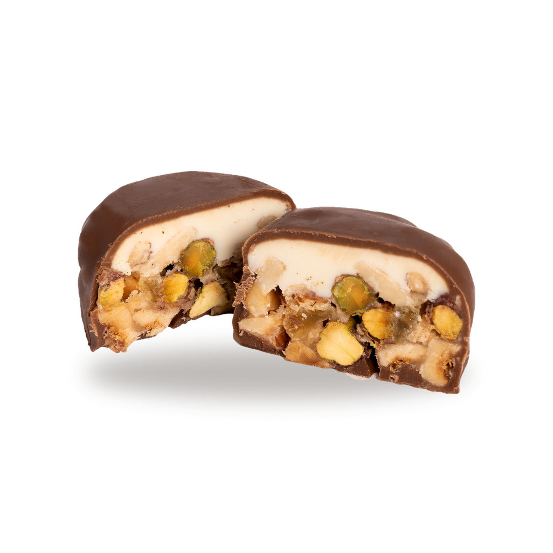 A dark chocolate Snayniyeh broken open, showing the cashew and pistachio inside