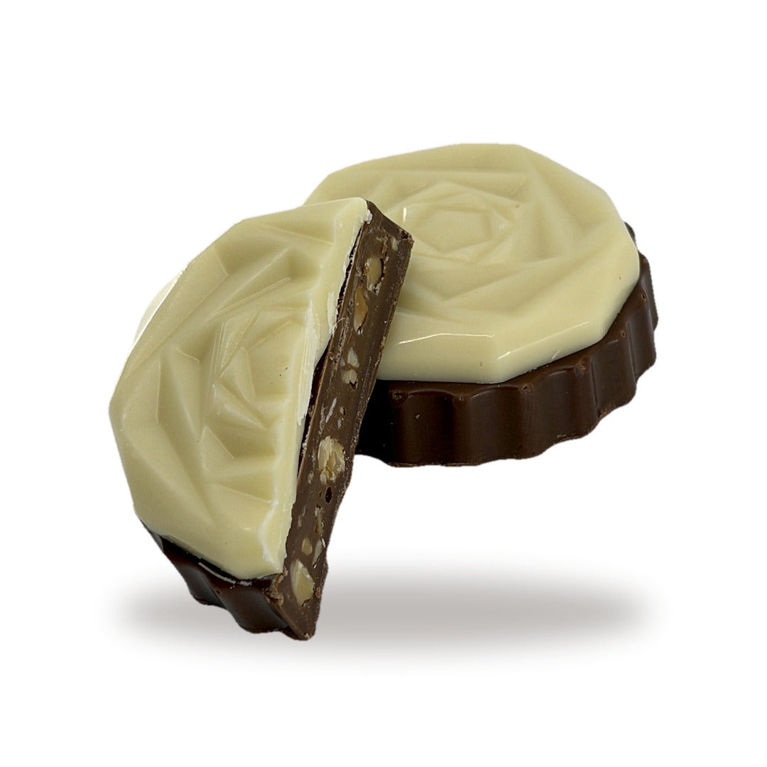A Flower White Praline cut open, showing the almond and hazelnut praline inside under the white chocolate flower