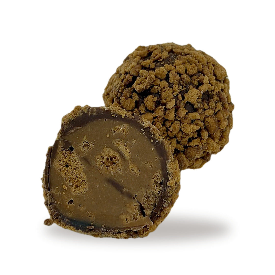 A Caramelized Biscuit Truffle cut open, showing the smooth biscuit filling inside the milk chocolate shell and crumb coating
