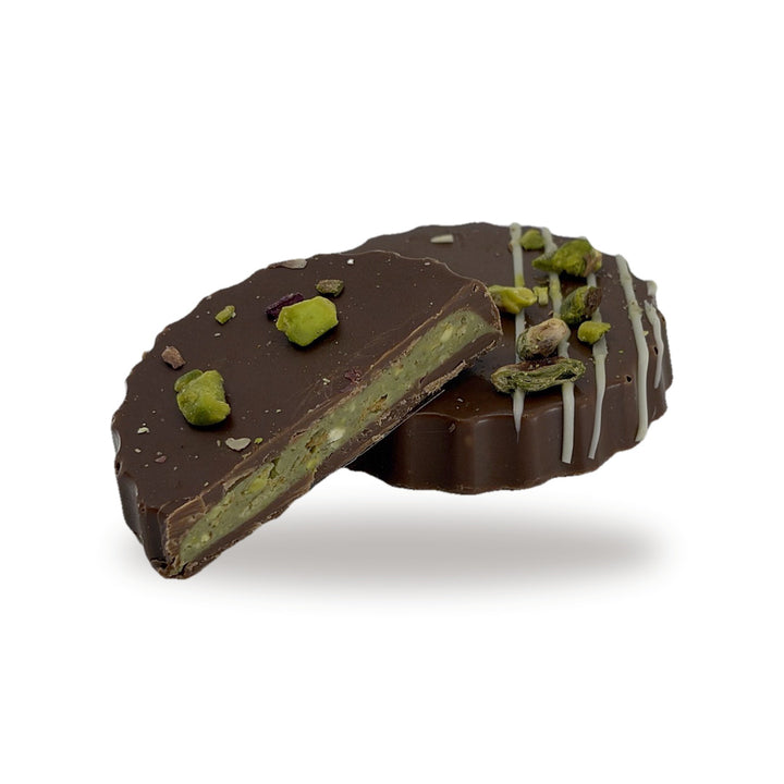A Pistachio Kunafa cut open, showing the green pistachio and kunafa filling inside the milk chocolate