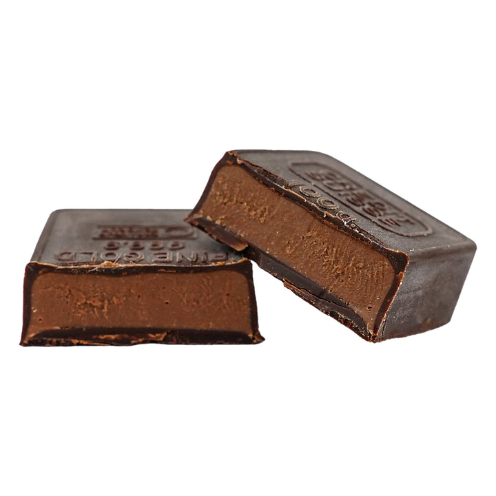 Dark chocolate praline square cut open to show smooth hazelnut filling.