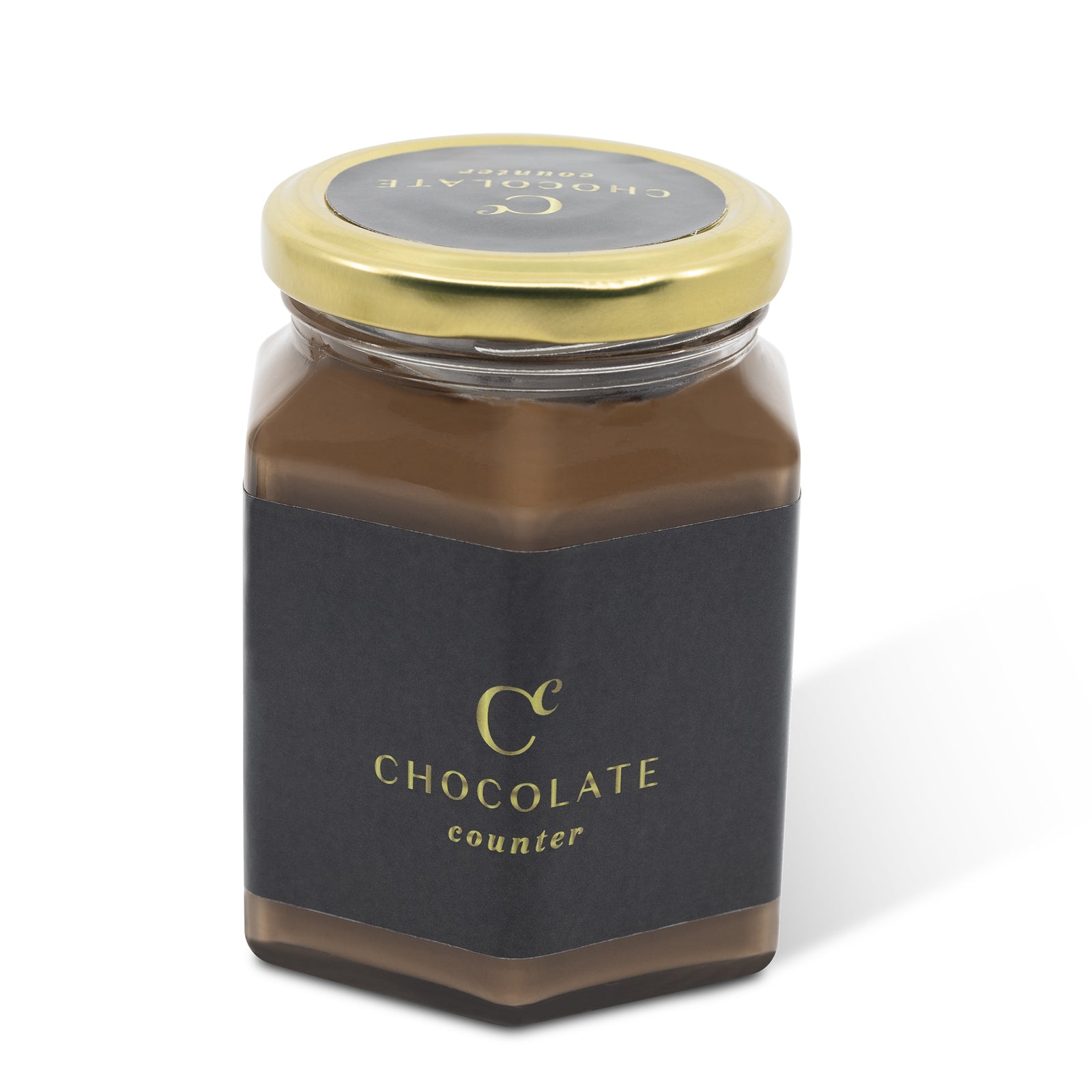 Glass jar filled with Chocolate Counter hazelnut spread, gold lid and black label