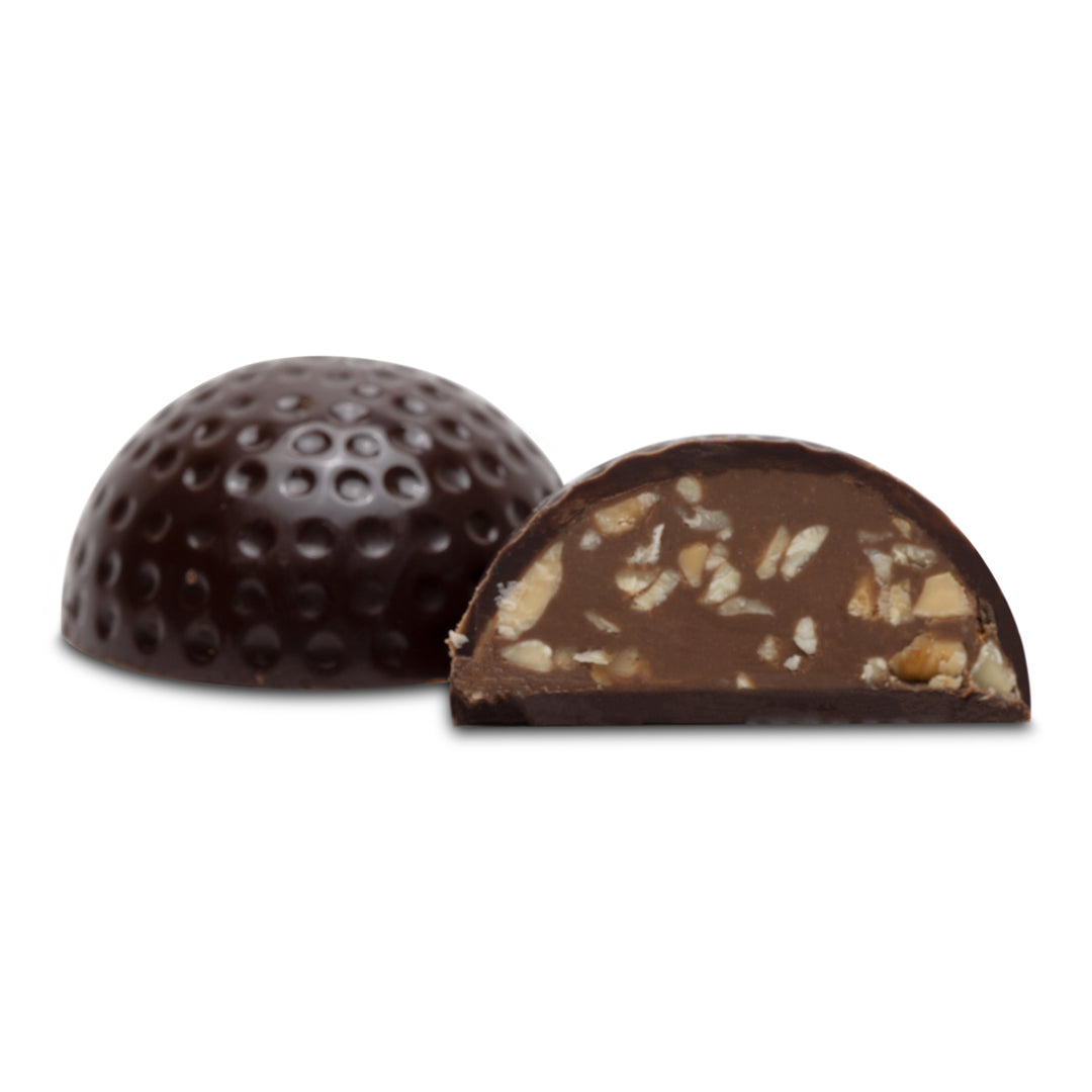 Cross-section of dark chocolate ball showing praline and nut filling.